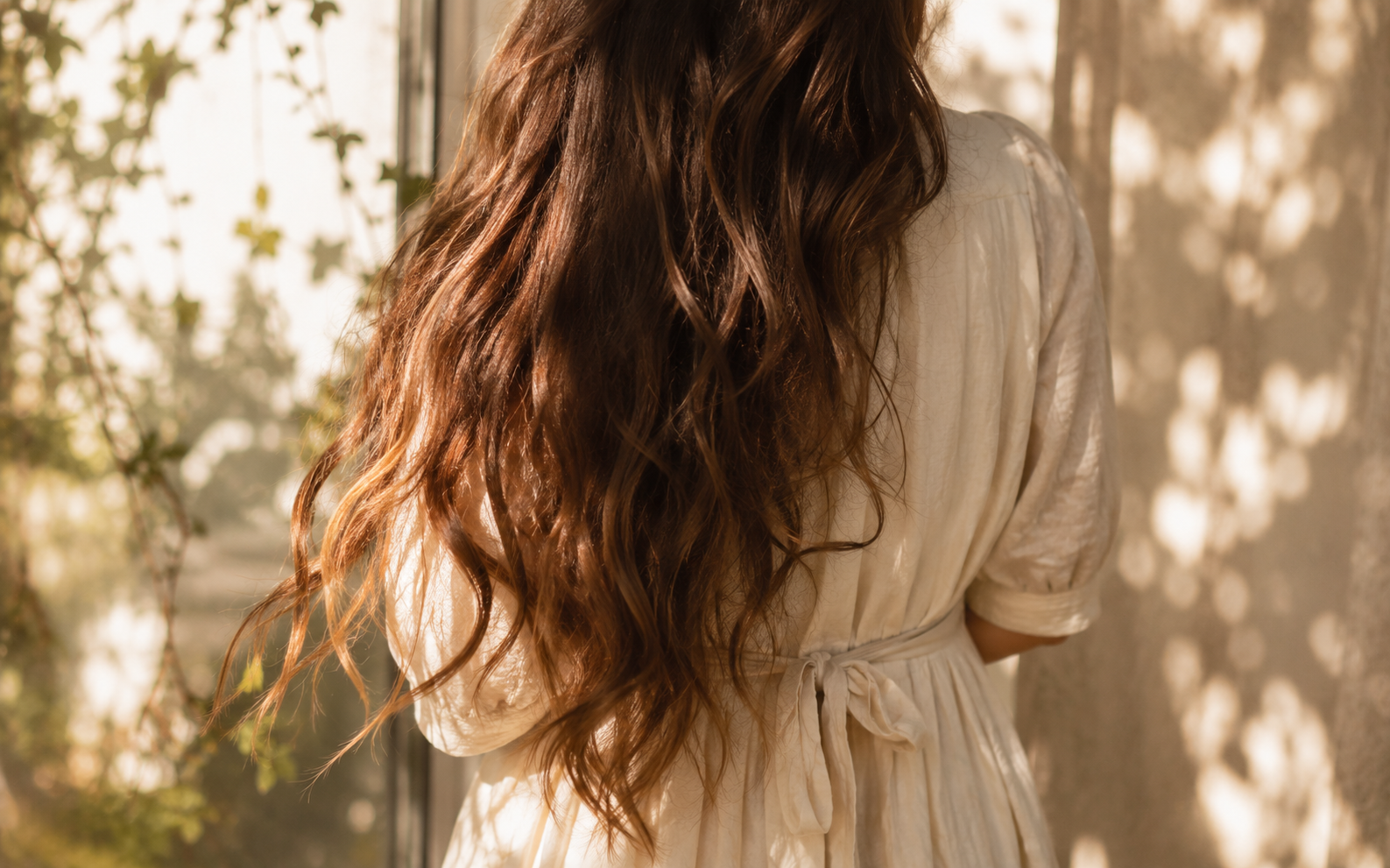 Long flowing brunette hair photographed from behind, sunlight catching the strands